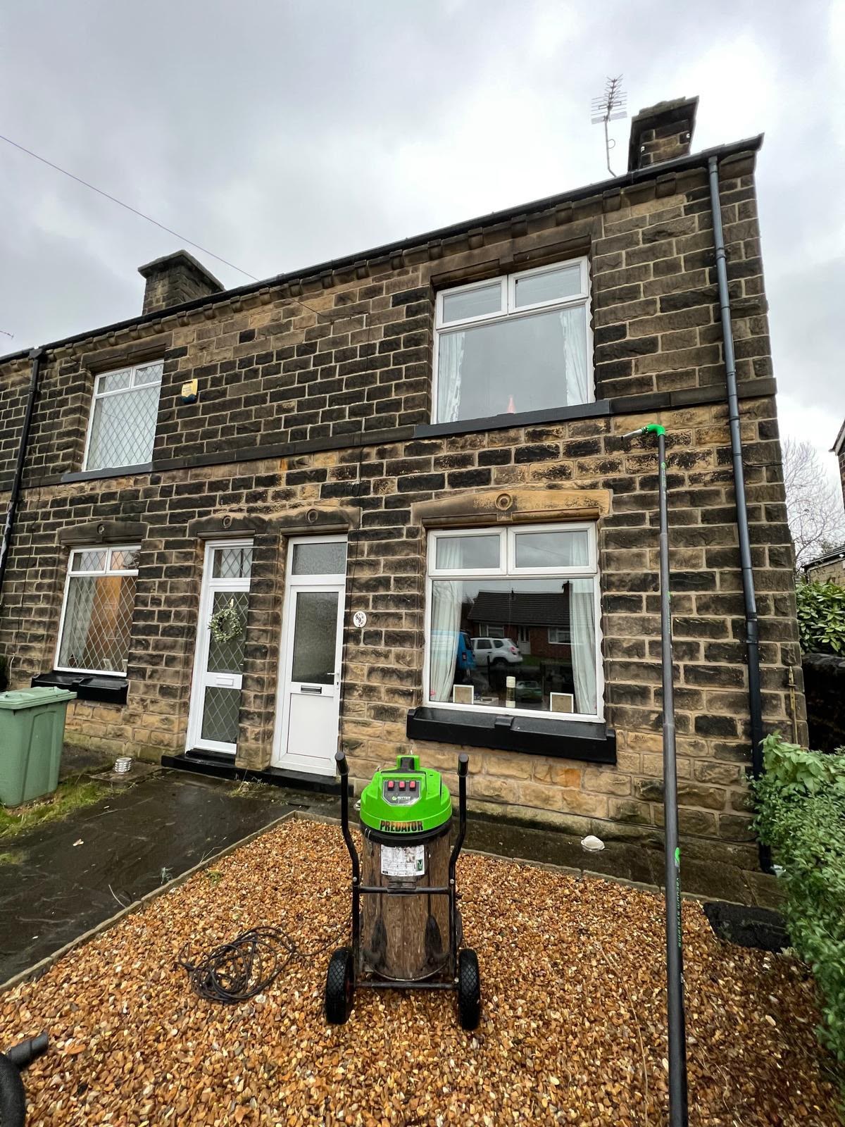 Gutter vacuum clearing the gutters of a stone-fronted terraced house